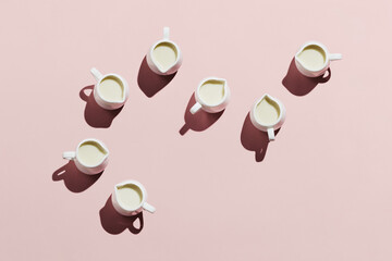 Flatlay of white creamers with oat milk on pastel pink background