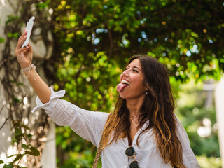 A young caucasian female smiling and using her phone while walking in the street