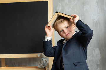 Children go back to school. Funny little boy near a blackboard. A child from elementary school with a books