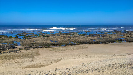 Sea waves breaking on rocks in Esposende, Portugal. Sea, beach boulders, pebble shore and waves in the morning.