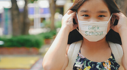 Back to school. asian child girl wearing face mask with backpack  going to school .Covid-19 coronavirus pandemic.New normal lifestyle.Education concept.