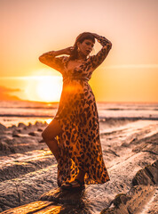 Lifestyle with sunset, a young woman in a long leopard dress on the beach of Sakoneta in the...