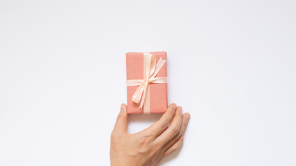 Hand holding pink gift box on white background. top view, copy space