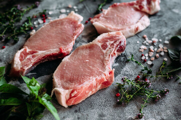 Raw pork steak on a bone on a table with pepper and salt