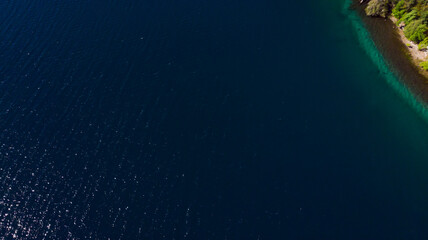 Aerial view of a forest lake. Aerial view of the blue lake and green forests on a sunny summer day. Top view of Patagonia.