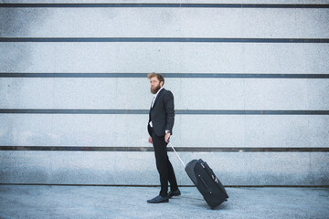 Business man at airport with suitcase. Young businessman goes to check in at the airport and pulls a suitcase. Businessman with baggage in airport.