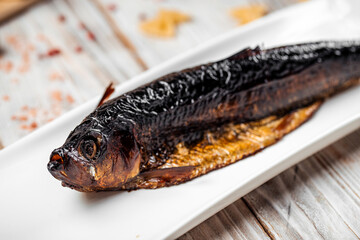 Smoked herring fish on a plate light wooden table