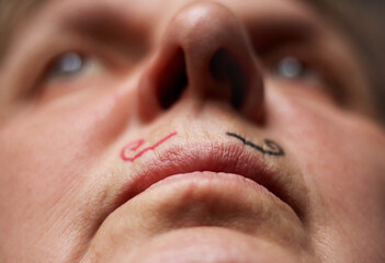 Obraz premium Female face with hand drawing mustache in black and red color, close up