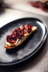 French baguette with hot Camembert cheese with jam in black plate