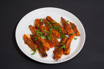 Spicy Tunisian carrots on a white plate against a black studio background