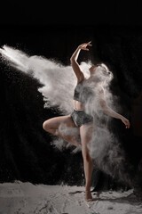 Obraz na płótnie Canvas Girl dansing with flour on black background one person