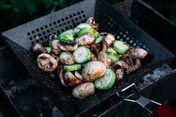 Mushrooms zucchini cook on a barbecue on the street