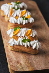 Choux pastry. Protein cream eclairs garnished with mandarin and mint.