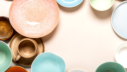Many different ceramic plates and bowls on a light background top view, space for text. Different tableware. Empty multicolored plates flat lay, copy space.