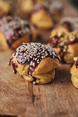 Choux pastry. Profiteroles with butter cream garnished with chocolate sauce, nuts and sesame seeds.