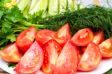 chopped tomatoes, cucumbers and greens are on a plate, close-up