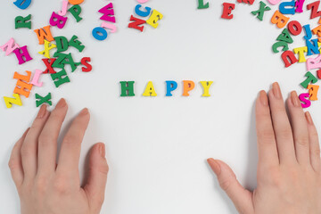 Joy and happiness concept. Female hands lay out the word happy from colored letters