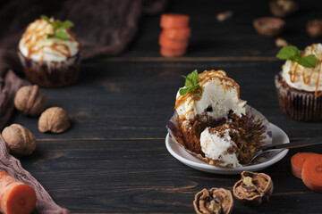 Carrot cupcakes stuffed with caramel and walnuts. Cupcakes with cream cheese cream and icing sugar. The dessert is decorated with mint and caramel.