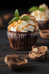 Carrot cupcakes stuffed with caramel and walnuts. Cupcakes with cream cheese cream and icing sugar. The dessert is decorated with mint and caramel.