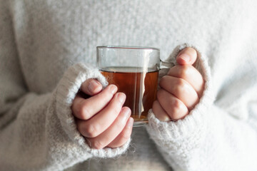 Woman with white wool sweater holding a cup of hot