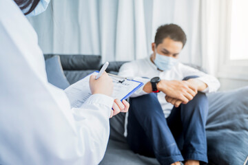 Asian Medical healthcare clinic doctor examining diagnosing male worry depressed anxious patient clipboard writing wearing surgical mask protection infection disease, working at home modern office