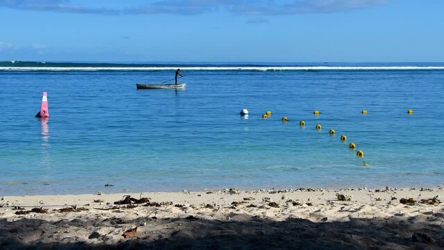 Fisherman on pirogue (boat) on tropical sea with crashing waves - Mauritius