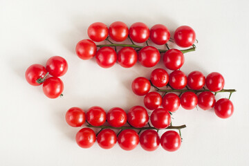 Three sprigs of cherry tomatoes on a light background. The view from the top