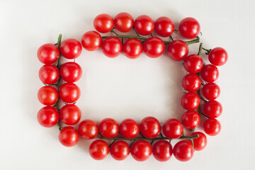 Four sprigs of cherry tomatoes in the form of a frame on a light background. The view from the top. Space for text