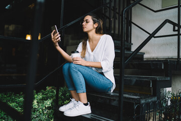 Obraz na płótnie Canvas Modern young woman using smartphone on stairs