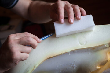 A person repairs the foam seat of a car.