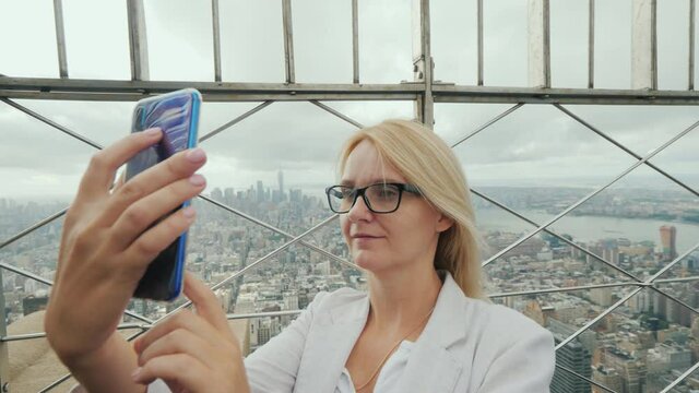 Woman tourist takes pictures of herself in the background of the panorama of New York
