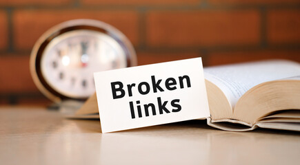 Broken links concept text on a white background with a clock and an open book