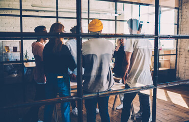 Back view of working team discussing ideas and strategies for startup project  meeting at coworking...