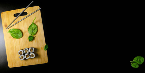 Maki Shiitake Sushi On a Wood Cutting Board With Metal Sticks On a Black Background
