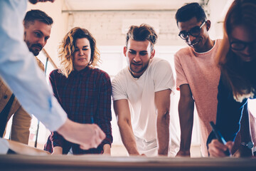 Smiling team members satisfied with productive job drafting together during meting in coworking space, successful working team of architects planning project and sharing ideas with each other