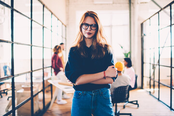 Half-length portrait of attractive female leader of working crew spending time in coworking...