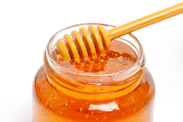 golden bee honey in a glass jar and honey dipper
