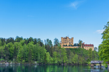 Fototapeta premium View of the Hohenschwangau Castle. Panorama of a lake with a castle and a pier. Germany, Bavaria, Schwangau.