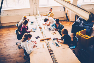 Top view of multiracial group of students having training lesson in classroom using technology,crew of creative designers collaborating during brainstorming session in coworking office sitting 