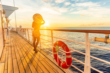 Cruise ship luxury vacation travel woman watching sunset on deck. Elegant lady tourist with sun hat relaxing on Caribbean holidays.