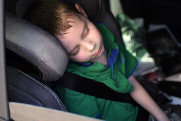 The boy is hot in the car. The child is tired during the trip.