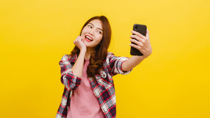 Smiling adorable Asian female making selfie photo on smartphone with positive expression in casual...