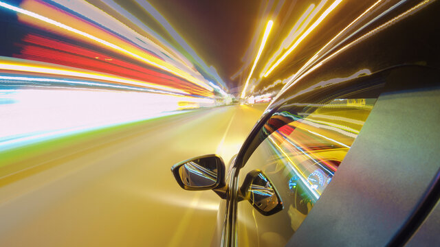Driving a car in the city at night. The camera on the hood of the car. Hyperlapse in the evening in the center of the city on the highway. Abstract soft glowing lines.