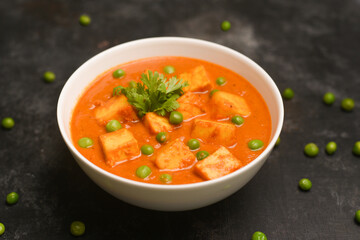 Matar Paneer curry recipe made using cottage cheese, green peas, served in bowl. selective focus Delhi, Rajasthan India. Top view Indian veg curry on dark background. side dish of Roti, Chapati, naan