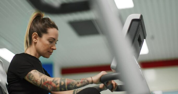 woman exercising with elliptical cross trainer at gym.Side view close-up, slow motion. Woman training at elliptical bike. Woman pedaling at gym