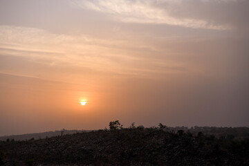 Silhouette of a tree against the setting sun on the heights of a mountain.