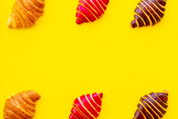 Frame of croissants - fresh bakery on yellow background. Top view