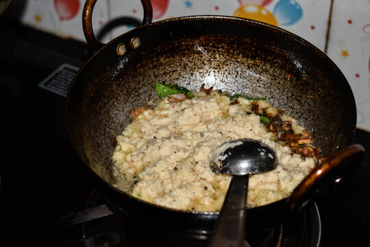 south indian cuisine - White coconut chutney preparation in a pan or khadai. Selective focus applied.