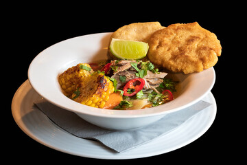 Strong beef broth with vegetables and beef on a deep white plate. Isolated on black background.