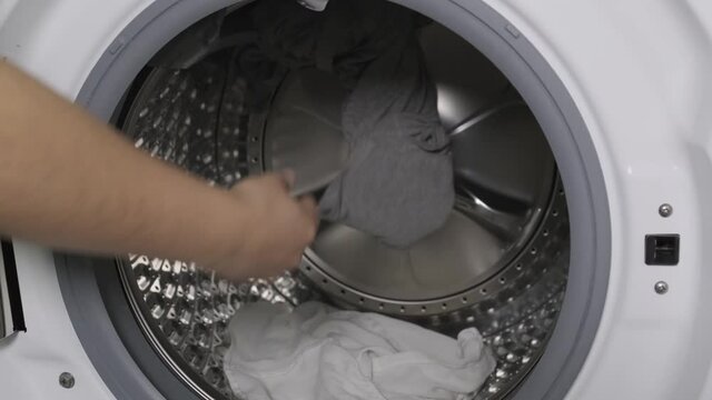 Unrecognizable person putting gloves and medical mask in a washing machine. New normality concept.